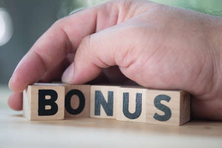 Block in word BONUS in man hand. Bonus is motivation in workの写真素材