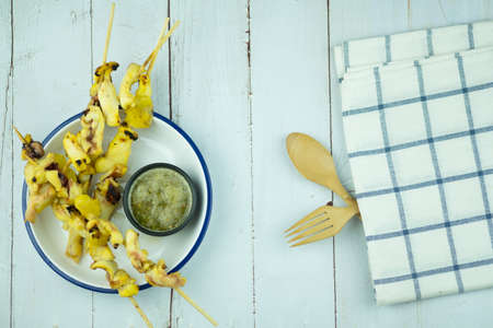 Close up squid grill with yellow ginger herb in wood stick served with hot and spicy sauce