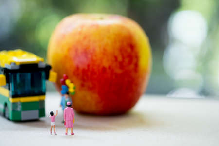 Miniature people: Childrens go to school with mother by school bus. Concept of back to school
