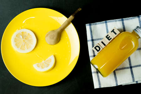 Bottle of fresh orange juice with slice fresh lemon on yellow plate. Creative food or diet food and creative picの写真素材