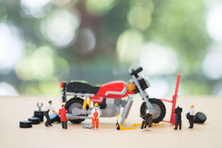 Miniature repairman: Team of change motorcycle tire. Concept of time to change seasonal summer or...
