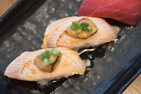 Foie Gras on top salmon burn sushi on black plate. Japan food