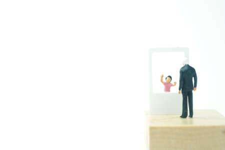 Miniature people. Father having video call with son on mobile phone. Communication and family conceptの写真素材