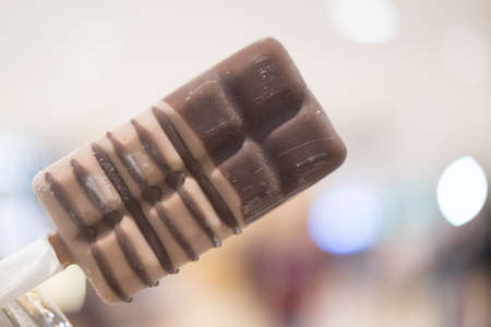 Coffee ice cream on a stick in young handの写真素材