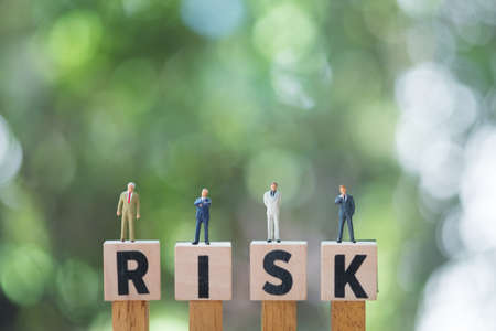 Miniature people group of businessmen stand on cube word with risk. Risk analysis for investment. The concept business risk assessment or management conceptの写真素材
