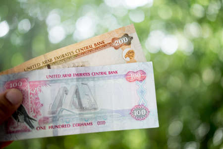 Persons hand giving the Currency of the United Arab Emirates (UAE) - Two hundred and one hundred...