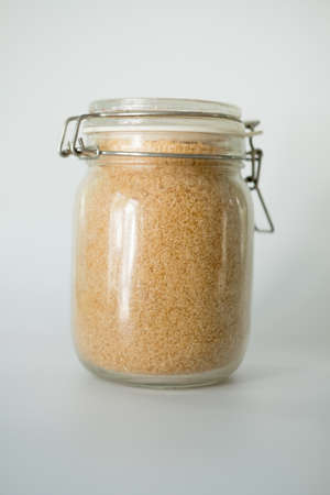Brown or cane sugar in glass jar. Food ingredients
