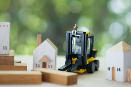 Miniature banker with yellow forklift. Concept of risks, lost property, seized, mortgageの写真素材