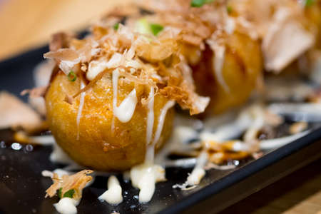 Takoyaki is a ball-shaped Japanese snack made of a wheat flour-based batter and cookedの写真素材