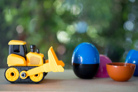Toy bulldozer carry egg toys open inside mini toy to surprise. Concept of delivering toy for funの写真素材