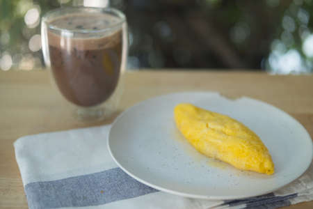 Egg omelet roll served with iced coffee on wood table