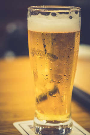 Chilled glass of light beer on wood table in pubの写真素材