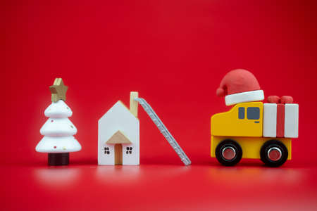 Yellow toy truck carry present sent to kid at home by santa on red background. Holiday delivery.の写真素材