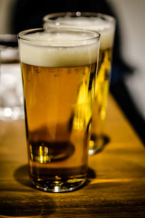 Two glasses of beer with foam on wood table, close-upの写真素材