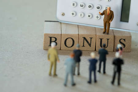 Miniature people: boss calculate earnings profits of the business for pay bonus to staff in annual. Yearly bonus concept. Bonus is motivation in workの写真素材