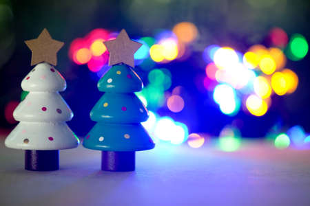 Miniature two wooden toy Christmas tree on lighting background. Christmas holiday celebration conceptの写真素材