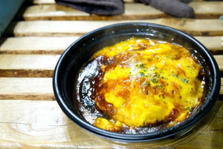 Omelet with cheese and sauce on rice in black take away bowl. Selective focusの写真素材