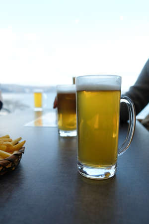 A beer glass on table in winter weather. Snow outside