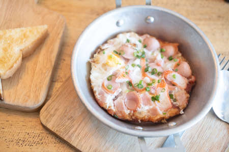 Fried egg in pan with spring onion, sausage and porkの写真素材