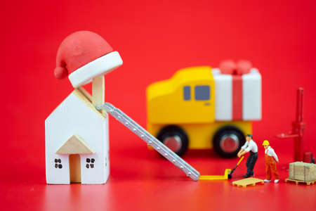 Miniature people creating Christmas decorations on red background. Creative concept in Christmasの写真素材