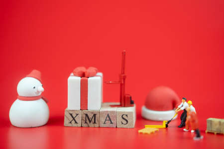 Miniature people: worker team prepare ornament for decoration in Christmas season on red backgroundの写真素材