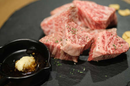 Premium grade of sliced Japanese beef on black stone plate prepared for grilledの写真素材