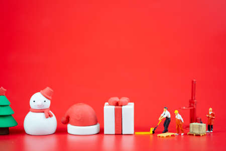 Miniature people creating Christmas decorations on red background. Creative concept in Christmasの写真素材
