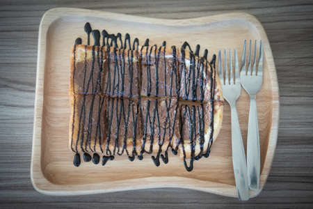 Sliced toast with chocolate and chocolate sauce on a wooden boardの写真素材