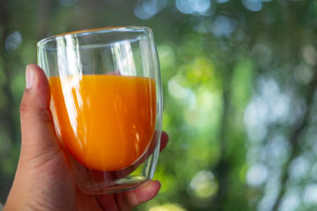 A glass of freshly squeezed orange juice in handの写真素材