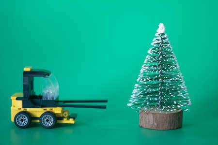 Excavator toy model move Christmas tree end of season on green backgroundの写真素材