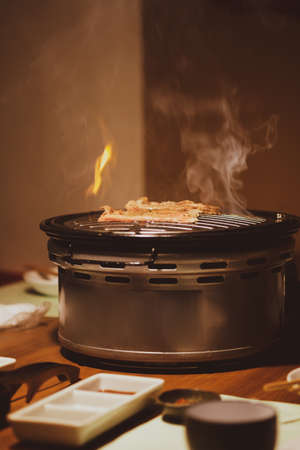 Pieces of marinated raw beef were put on grill with flame under the grill. Delicious food in Japan,
