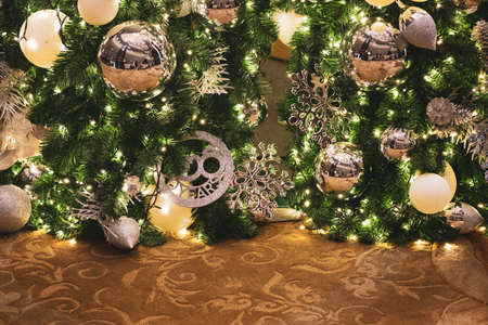 Christmas tree with golden balls on a green tree in a light interior. Close up.