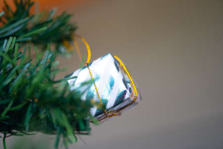 A silver box hanging on the branches of an artificial Christmas treeの写真素材