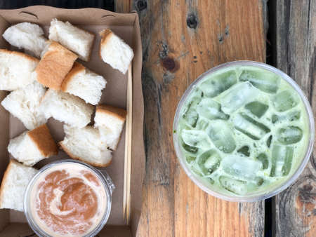 Slice of steamed bread and Thai tea custard delicious and iced green tea on wood table
