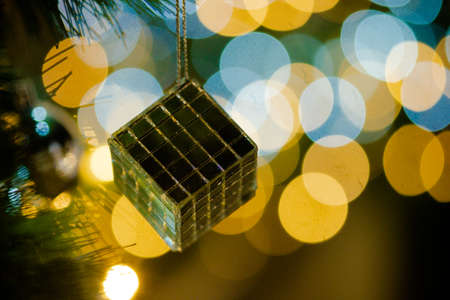 Silver box hanging on artificial Christmas tree and with lighting bokeh backgroundの写真素材