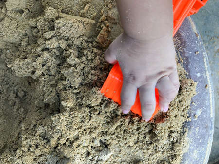 Child boy playing orange toy loader on sandbox at yard. Concept of play and learnの写真素材