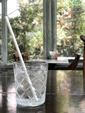 Water in a glass with ice and paper straw on wood tableの写真素材