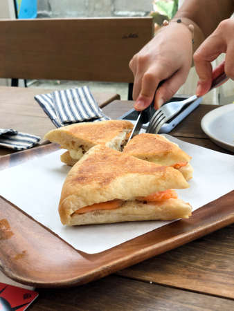 Woman eating triangle slice sandwich ham and cheese in breakfastの写真素材