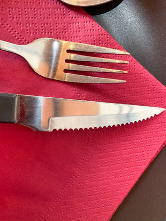 Silver knife and fork on red napkin. Close up