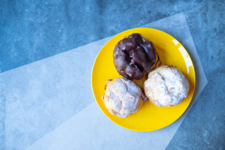 Set of cream pastry puffs on yellow dish ready for party