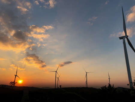 Wind turbine farm with power line and power plant during beautiful sunset Alternative green energy...
