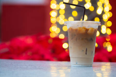 Iced latte coffee in plastic cup with blurry christmas lights backgroundの写真素材
