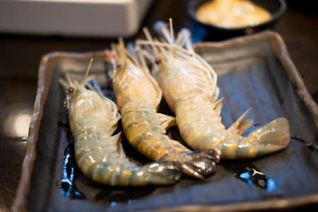 Three raw shrimp in black tray. Close up