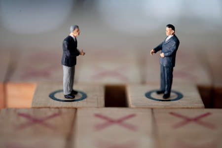 Miniature of executive businessman hand shaking and standing on wooden blocks. Business deal or agreement and success conceptの写真素材