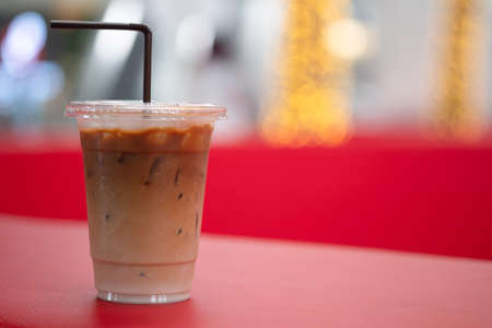 Iced latte coffee in plastic cup on red table