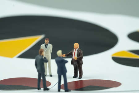 Miniature people, businessman in meeting on circle chart paper for graph analysis. Meeting or Discussion using as background business conceptの写真素材