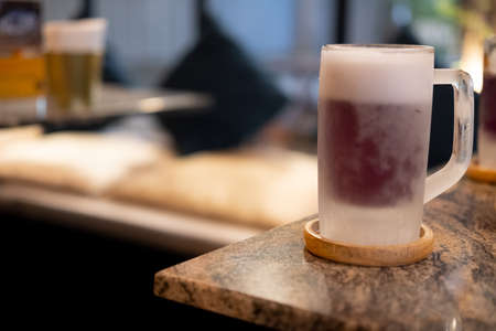 Mug of purple cold beer on table at restaurant
