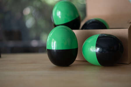 Plastic toy in the shape of a green-black egg on wood tableの写真素材