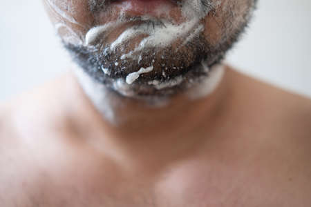 Close up portrait of a handsome bearded man with shaving foam on his face ready to shaveの写真素材