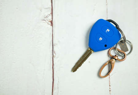 Blue car remote key cover silicone with chain on wooden table. Empty space for designの写真素材